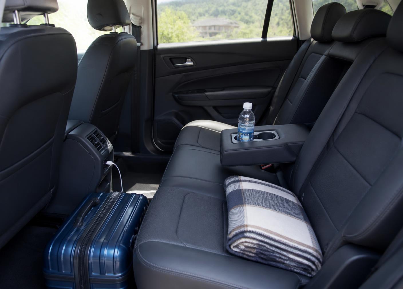 Habitacle arrière propre et soigné d'un véhicule moderne, bouteille d'eau, câble de recharge et bagage cabine
